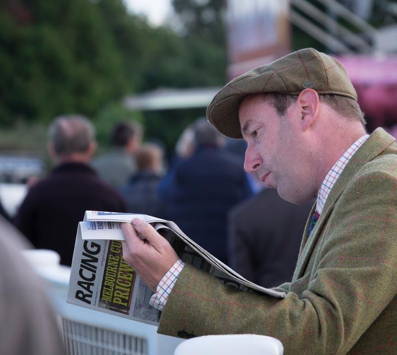 A male racegoer reading Racing Post newspaper.