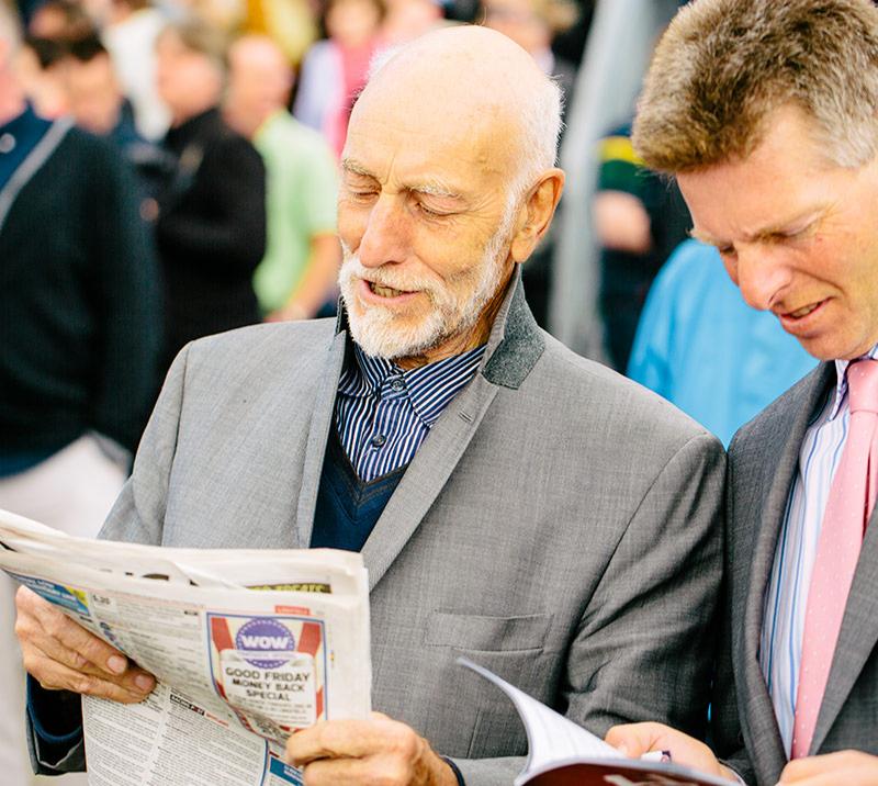 Two gentlemen reading through racing tips.