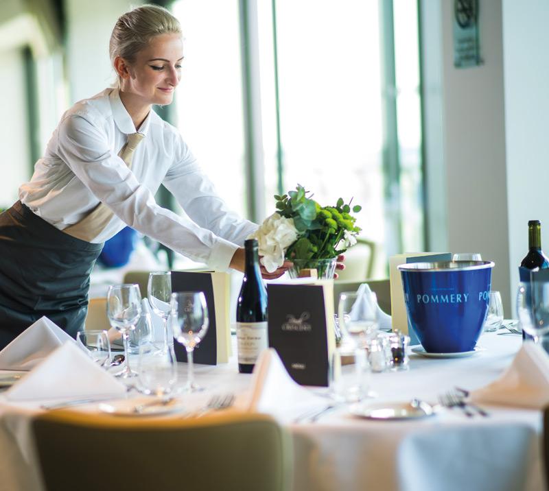 A waitress prepares the flower on diners tables before guests arrive at the racecourse.